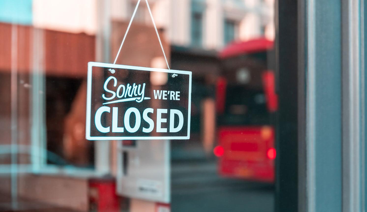 looking through a glass shop door at a CLOSED sign